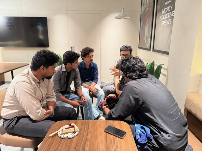 Five guests leaning in around a small table